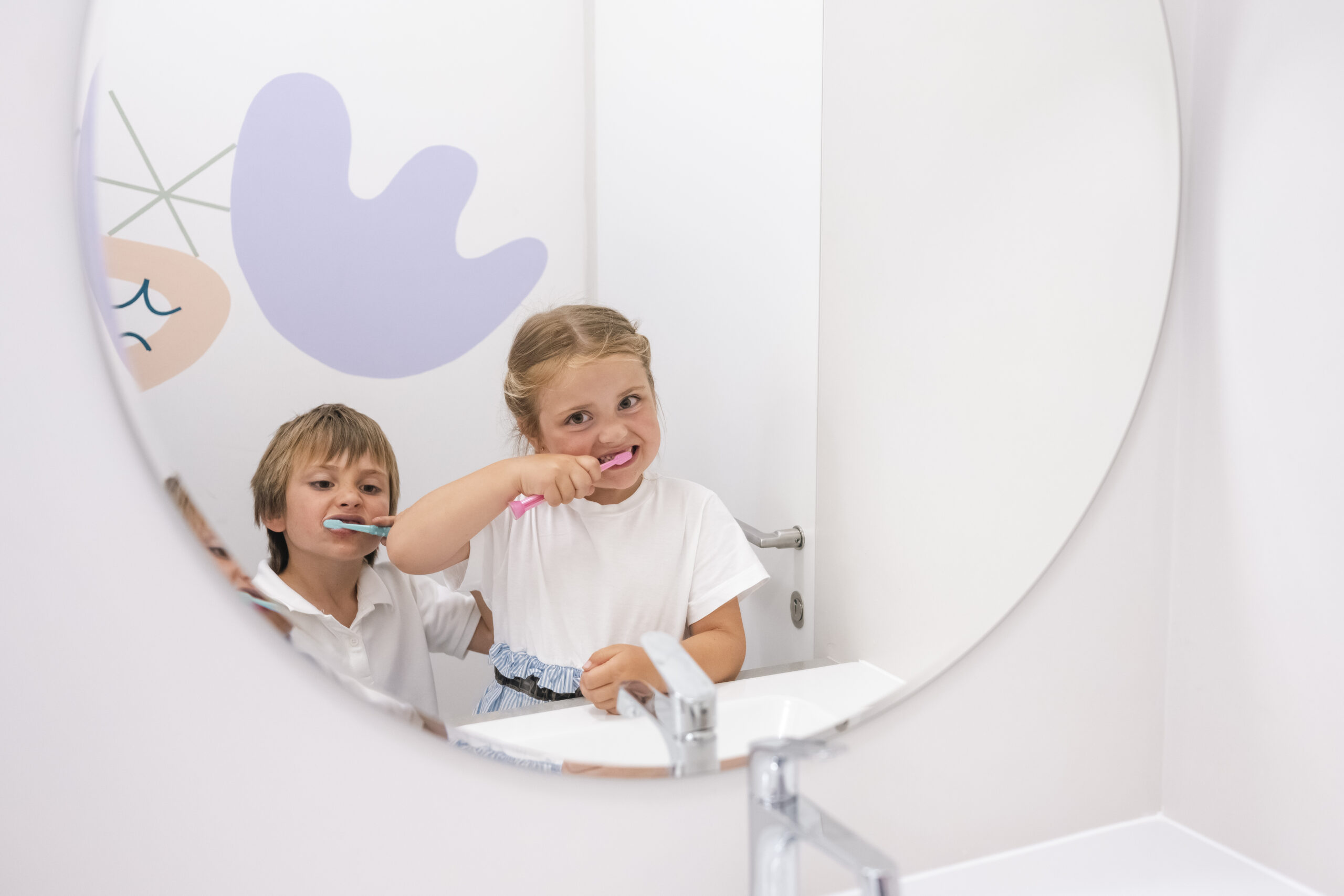 Děti si čistí zuby kartáčkem před zrcadlem při nácviku správné ústní hygieny