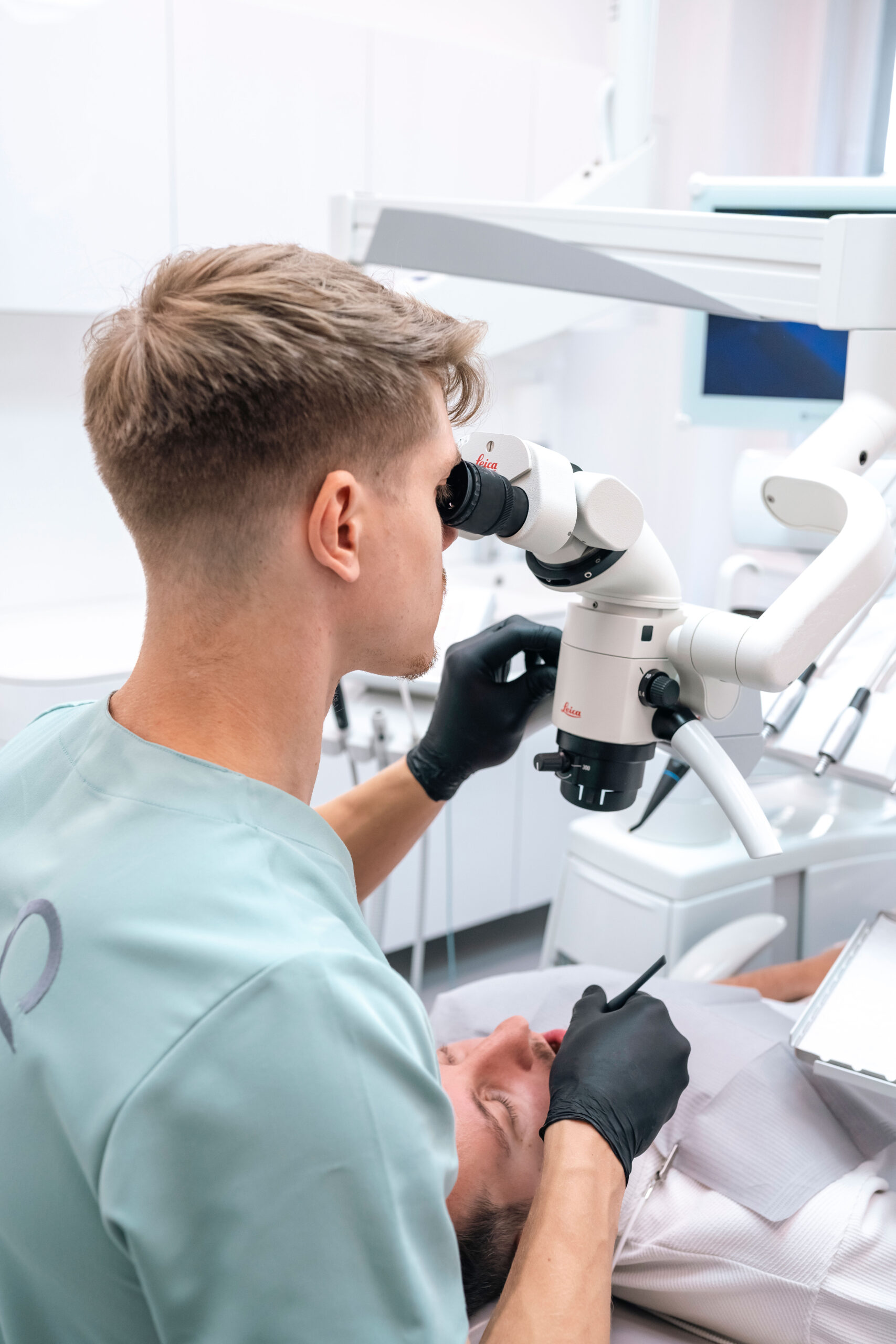 Zubař ošetřuje pacienta s použitím dentálního mikroskopu