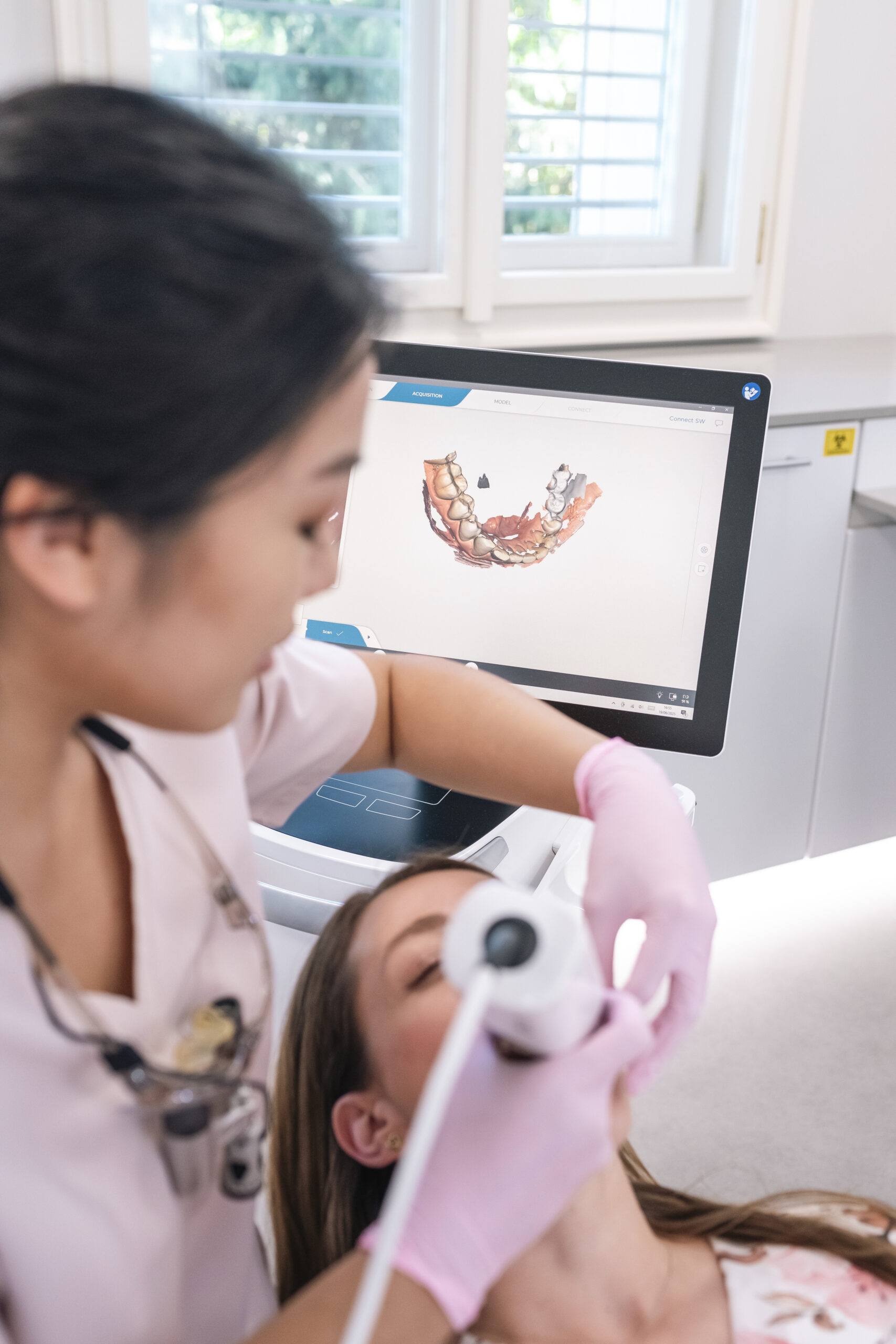 Dentistka provádí digitální sken chrupu pacientky, na monitoru je 3D model zubů