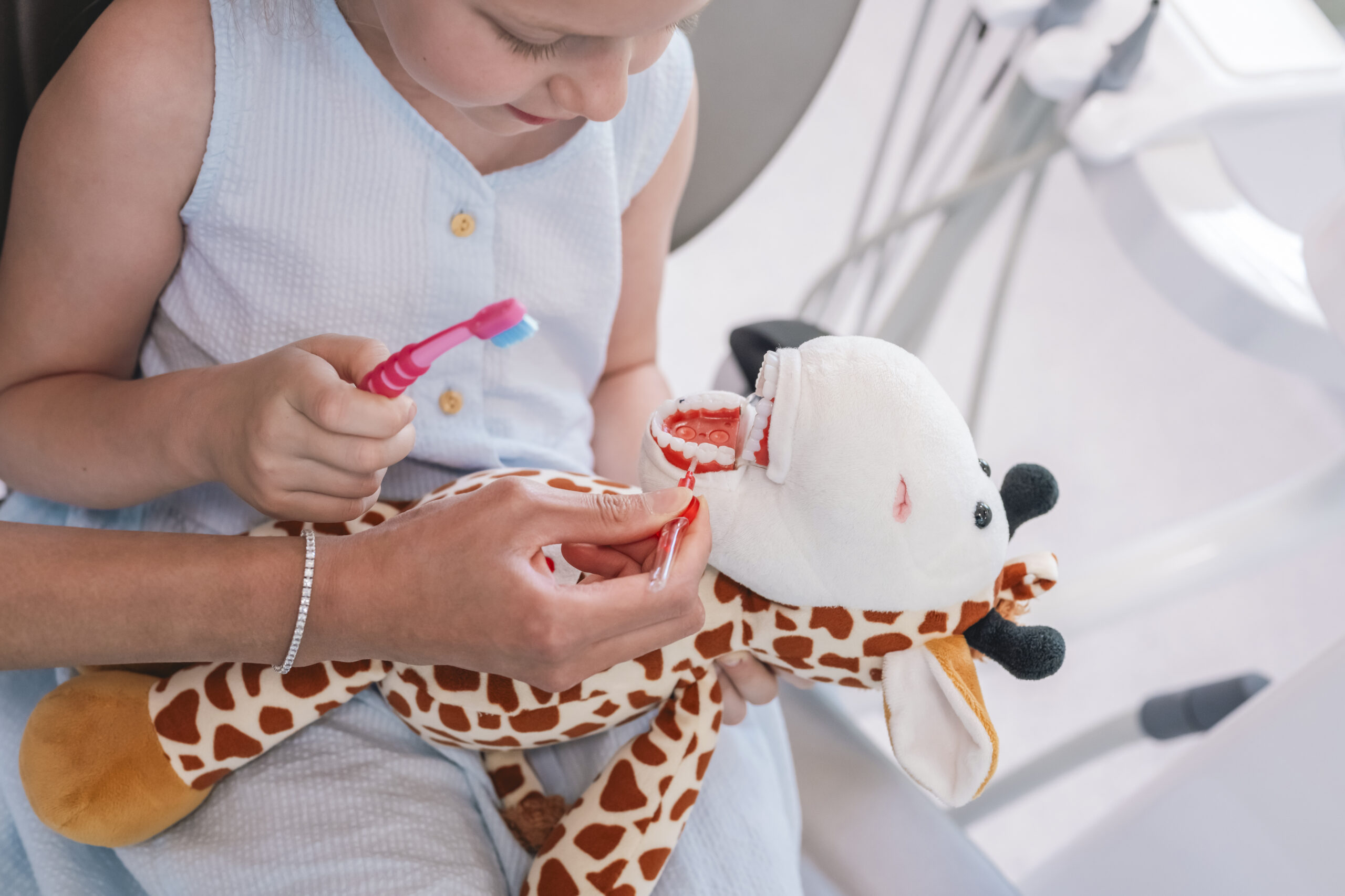 Girl learning proper tooth brushing on a dental model