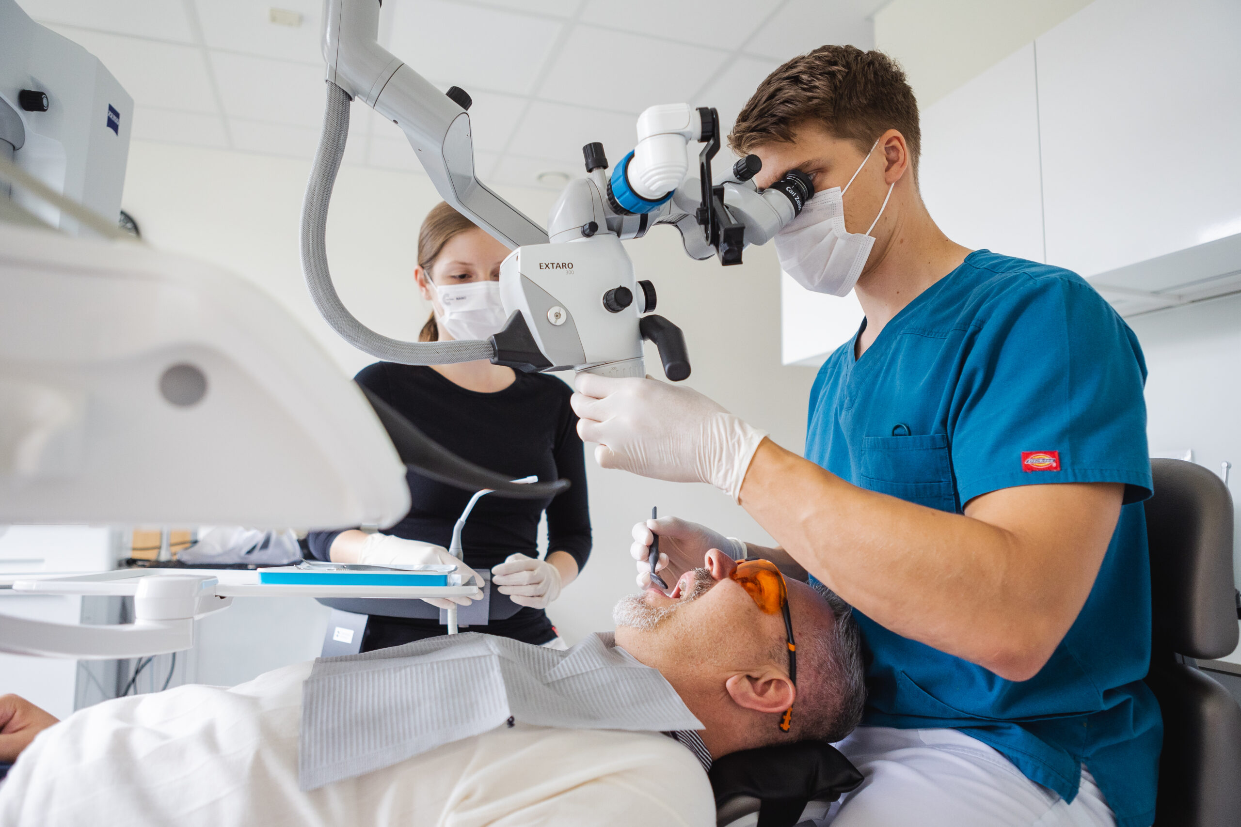 Dentist performing a dental procedure using a dental microscope in a modern dental clinic
